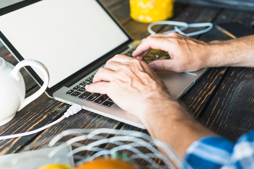man-s-hand-typing-laptop-wooden-desk